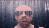 a man wearing sunglasses is standing in the rain .