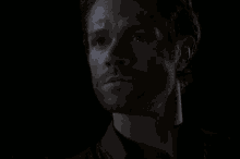 a close up of a man 's face with a beard in a dark room .