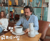 a man sits at a table with a stack of cups on it