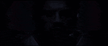 a close up of a man 's face with his eyes closed in a dark room with red lights behind him .