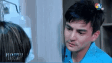 a man in a blue shirt is talking to a woman in a room with a sign that says ' a ' on it