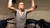 a bald man is sitting on a couch with his arms outstretched .