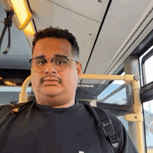 a man with glasses and a mustache is sitting on a bus with a sign that says no flexglas