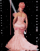 a woman in a pink gown is standing on a stage