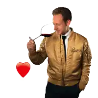 a man wearing a jacket that says arnold on it is holding a glass of wine