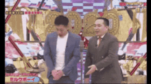 a man in a suit and tie is standing next to another man in a suit and tie on a stage .