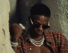 a young man wearing sunglasses and a plaid shirt