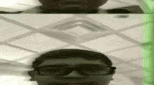 a man wearing glasses is standing in front of a mirror and looking at himself .