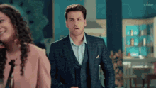 a man in a suit stands next to a woman in a pink jacket .