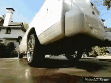 a white car is parked in a driveway with makeagif.com at the bottom of the screen