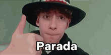 a young man wearing a hat and giving a thumbs up .