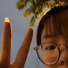 a woman wearing glasses is making a peace sign with her finger