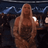 a woman with blonde hair is standing in front of a crowd in a stadium .