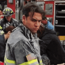 a man in a fireman 's uniform stands in front of a fire truck