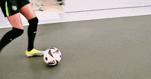 a person kicking a soccer ball with a wolfe tv advertisement in the background