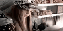 a woman wearing a zebra print hat is sitting in front of a shelf filled with figurines .