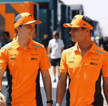 two men wearing orange shirts with dell technologies written on them