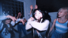 a group of young women are dancing in a room with their hands in the air