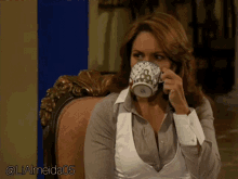 a woman sits in a chair drinking from a cup with a g on the back