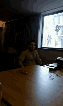 a man sits at a table in front of a window with a compass on it