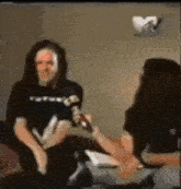 a man in a black shirt is being interviewed by a woman holding a microphone