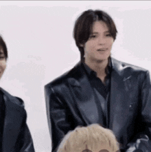 a man in a black leather jacket is standing next to another man in a black shirt .
