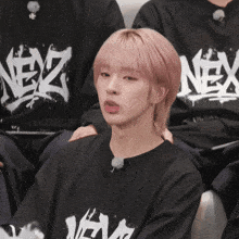a girl with pink hair is wearing a black shirt with the word nex on it
