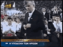 a man in a suit is dancing in front of a crowd on a tv screen that says kalaimapmapo