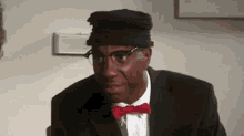 a man in a suit and bow tie is wearing a hat .