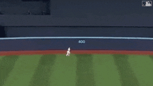a baseball player is running on the field with the number 400 on the wall behind him