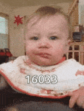 the baby is wearing a bib and making a funny face .