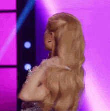 a woman with blonde hair is standing in front of a purple backdrop