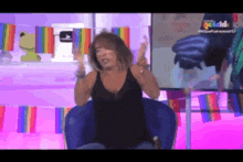 a woman in a black tank top is sitting in front of a screen that says goldd on it