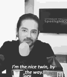 a black and white photo of a man talking into a microphone and saying i 'm the nice twin by the way
