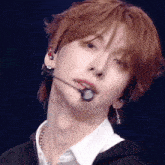 a young man with long red hair is wearing a microphone and earrings .