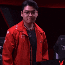 a man wearing a red jacket and a black shirt with the word mercedes on it