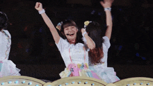 a girl in a white dress with flowers in her hair is holding her arms in the air