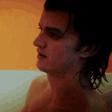 a man without a shirt is standing in front of a colorful wall