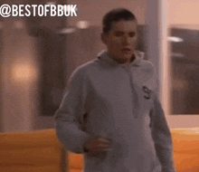 a man wearing a grey sweatshirt with the number 90 on it