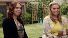 two women are sitting next to each other in a backyard and one of them is wearing a yellow top .