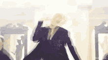 a man in a black suit is dancing in front of a crowd .