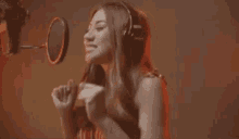 a woman is singing into a microphone in a recording studio while wearing headphones .