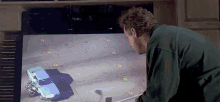 a man is watching a car crash on a television .