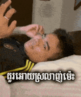 a man is laying on a bed with his hand on his face .