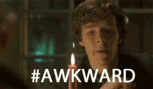 a man is holding a lit candle with the hashtag #awkward above him