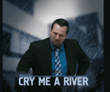 a man in a suit and tie is standing in the rain with the words cry me a river below him