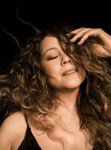 a woman with her eyes closed holds her hair in her hand