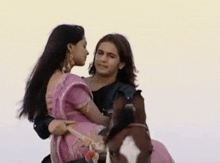 a man is riding a horse with a woman standing behind him .