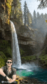 a man in sunglasses is standing in front of a waterfall .