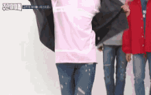 a group of people standing next to each other with one wearing a pink shirt and a red jacket .